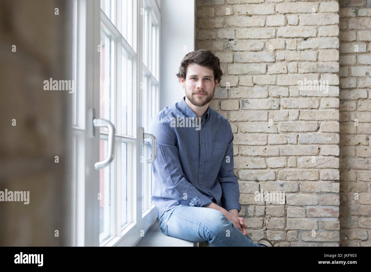 Giovane imprenditore seduta sul davanzale della finestra Foto Stock