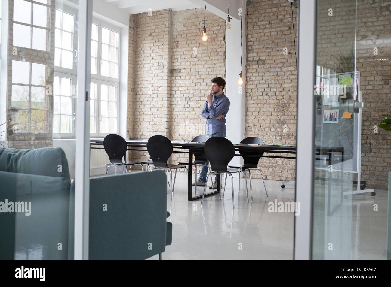 Il giovane imprenditore in piedi nel suo ufficio, pensando Foto Stock