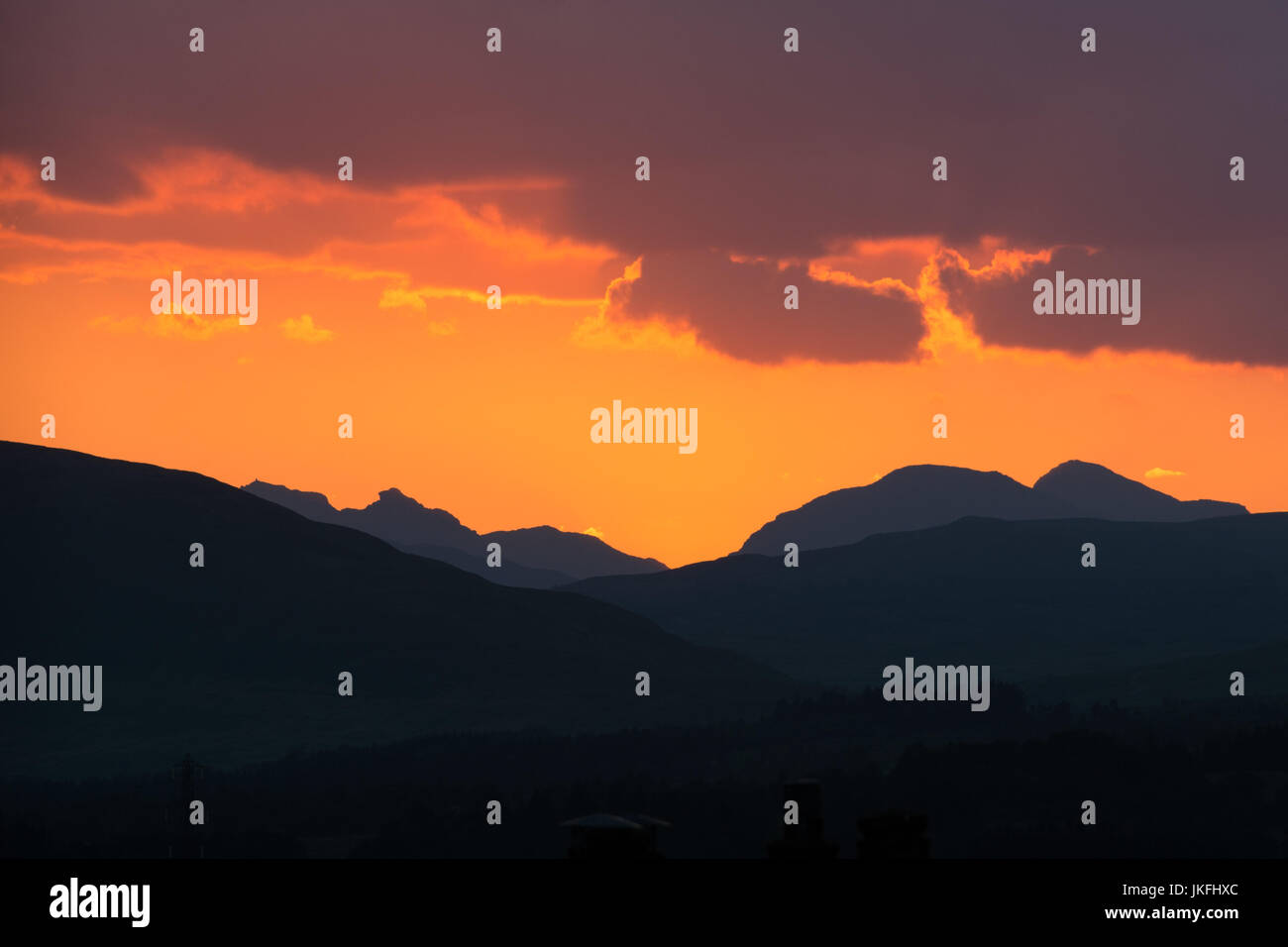Nelle Highlands Meridionali, Scotland, Regno Unito - 23 Luglio 2017: Regno Unito - previsioni del tempo - un bel colore arancione tramonto sul Southern Highlands della Scozia, con il contorno del distintivo vertice tre del ciabattino (Ben Arthur) sulla sinistra. Il cobbler è una montagna di 884 metri di altezza e la sua insolita rocky top è considerato rappresentare un calzolaio e il suo ultimo (un dispositivo conformato come un piede umano) Credito: Kay Roxby/Alamy Live News Foto Stock