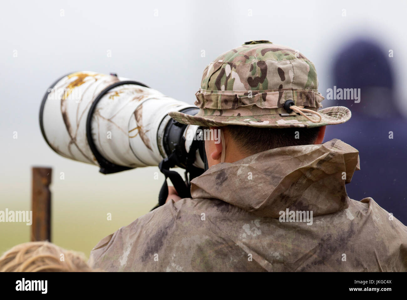 Fotografo professionista che indossa il camuffamento riprese con una fotocamera Canon e EF500mm f4 super teleobiettivo Foto Stock