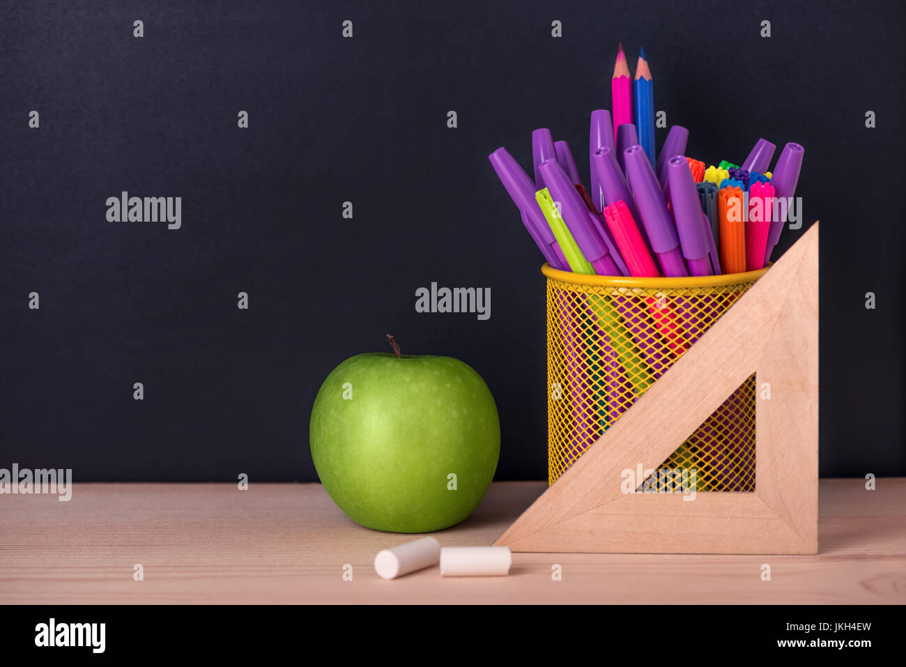 Il concetto di istruzione con mela verde, Righello o triangolo, pennarelli,  gessi sulla lavagna nera sfondo, close up Foto stock - Alamy