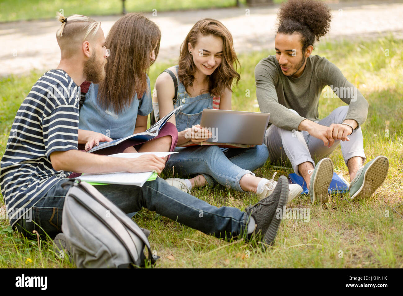 College amici seduti sul prato in campus, comunicante. Foto Stock