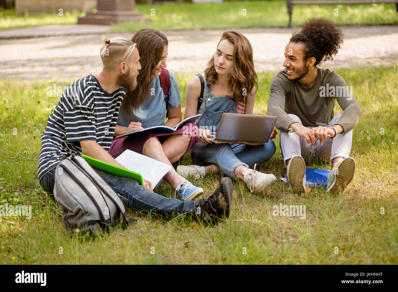 Campus studenti multietnica di apprendimento sul prato. Foto Stock