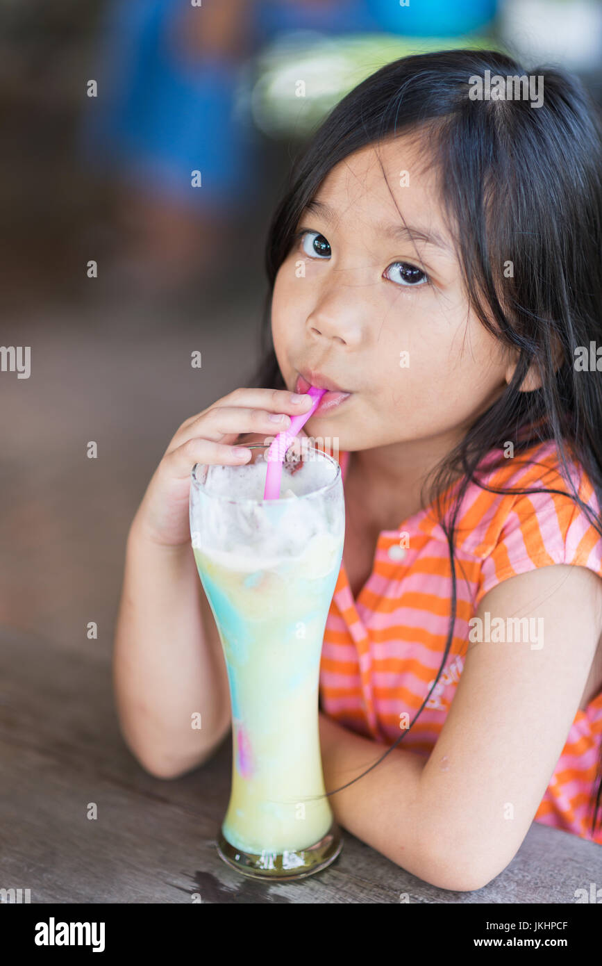 Carino ragazza piace mangiare ananas e mirtillo smoothie Foto Stock