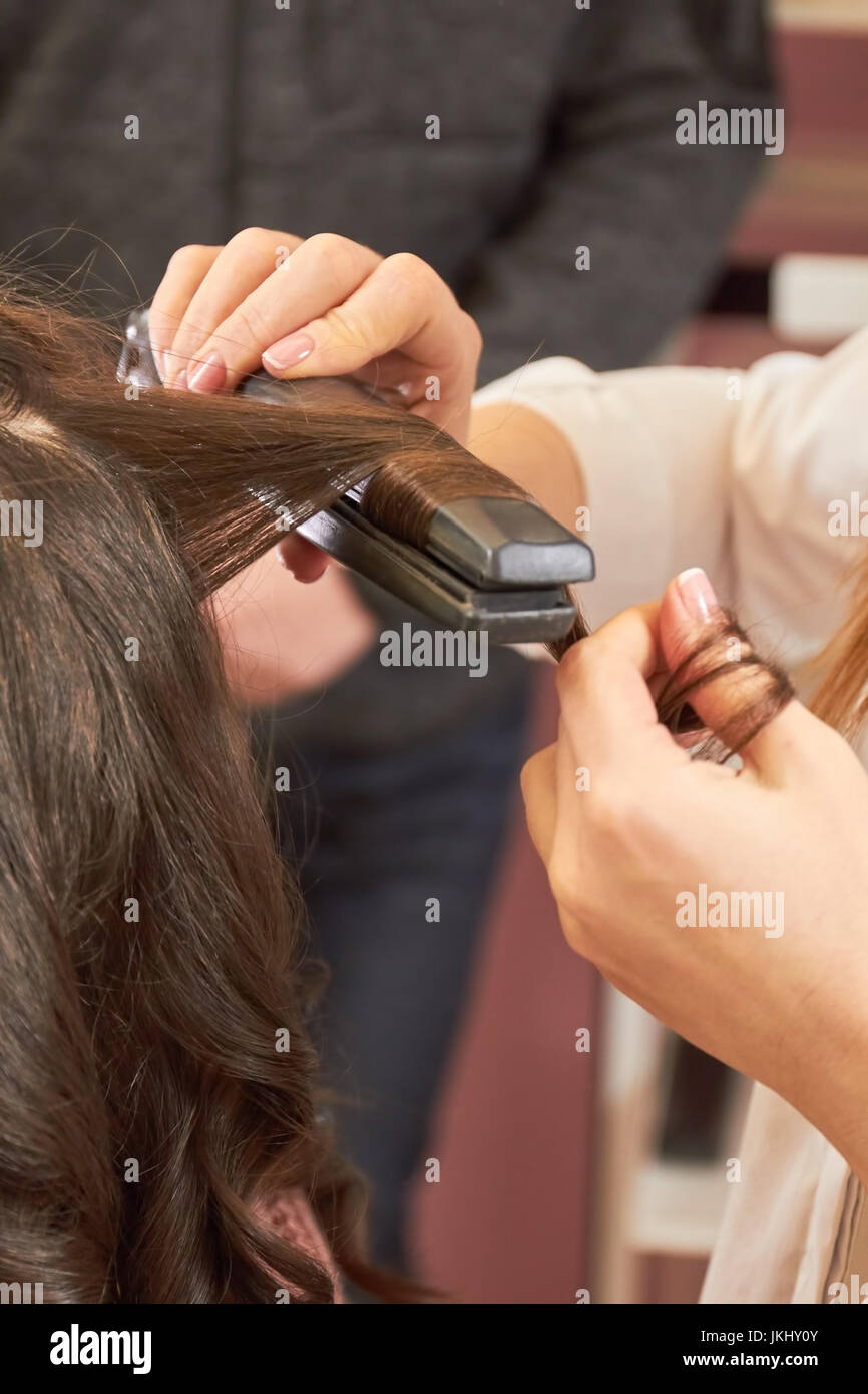 Mani con capelli Straightener. Foto Stock