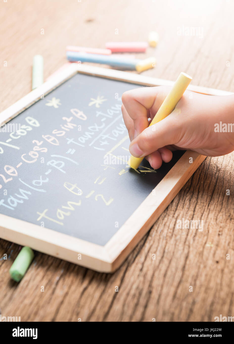 Poco la scrittura a mano su una lavagna completamento di equazioni matematiche su uno sfondo di legno Foto Stock