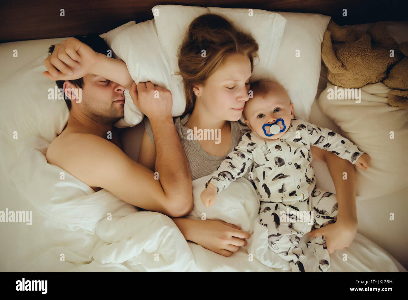 Padre, madre e bambino coccole a letto Foto Stock