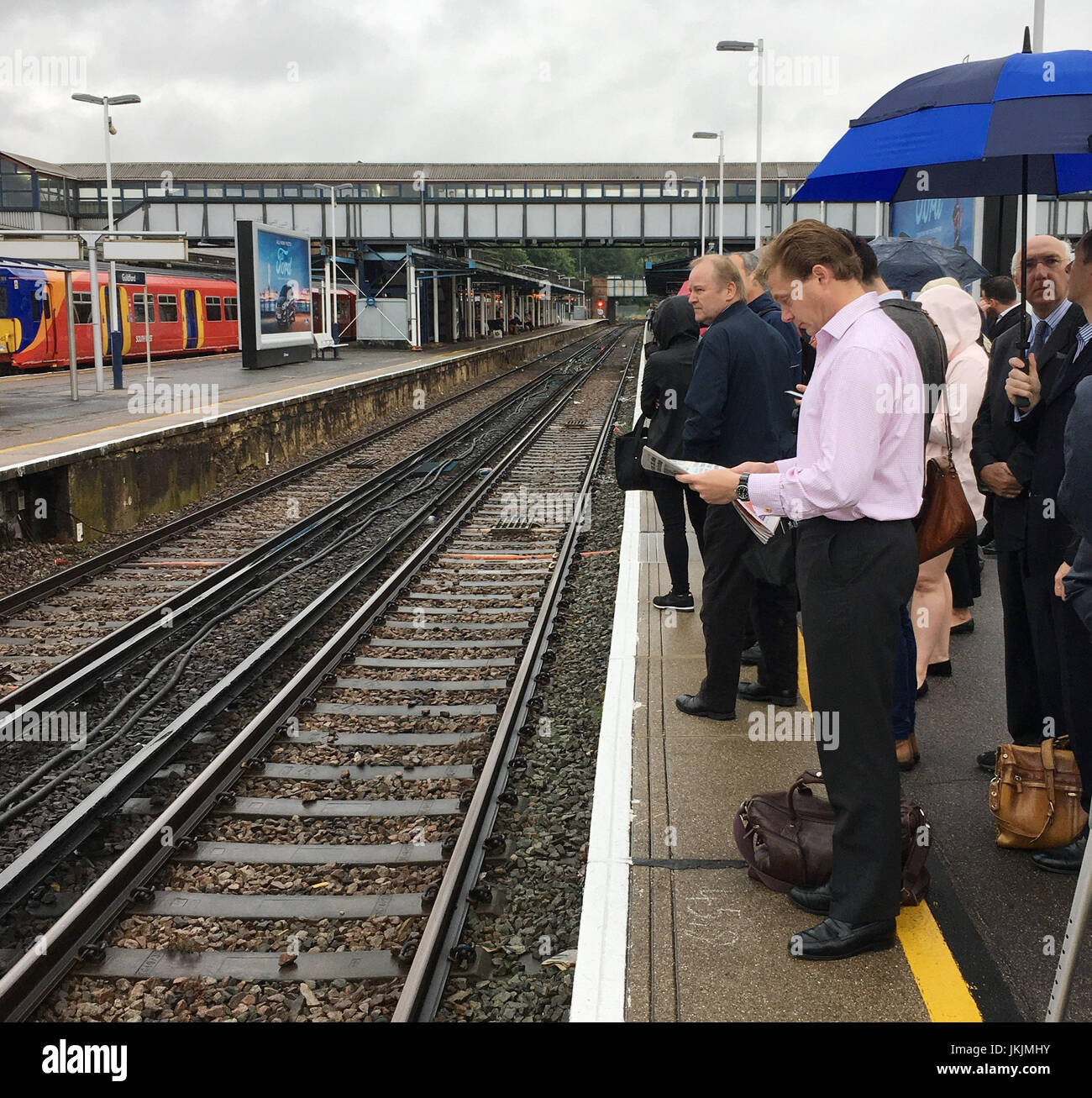 I passeggeri in attesa su di una piattaforma a Guildford Station dopo a sud-ovest di treni detti servizi in tutta la rete, compresi da e per Londra Waterloo, può essere annullato, ritardata fino a 90 minuti o rivisto dopo un segnale di guasto nella zona Earlsfiled. Foto Stock