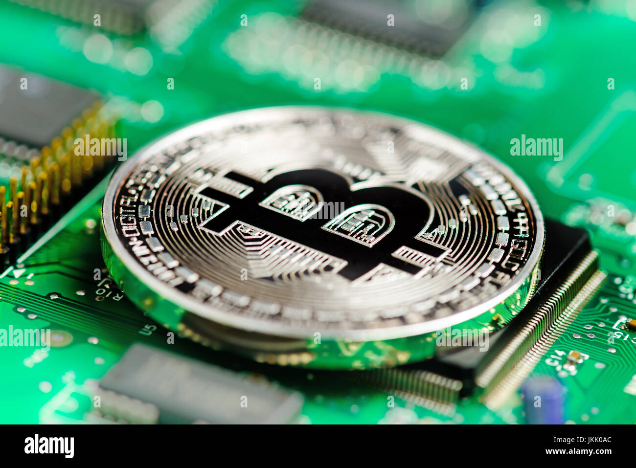 Argento Bitcoin moneta virtuale su una scheda a circuito stampato sullo sfondo Foto Stock