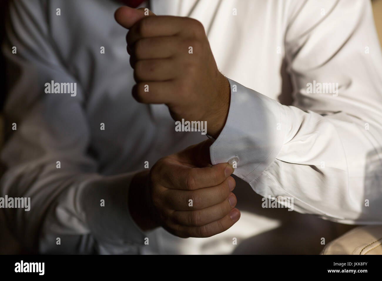 Imprenditore manicotto pulsanti camicia bianca, close-up delle mani Foto Stock