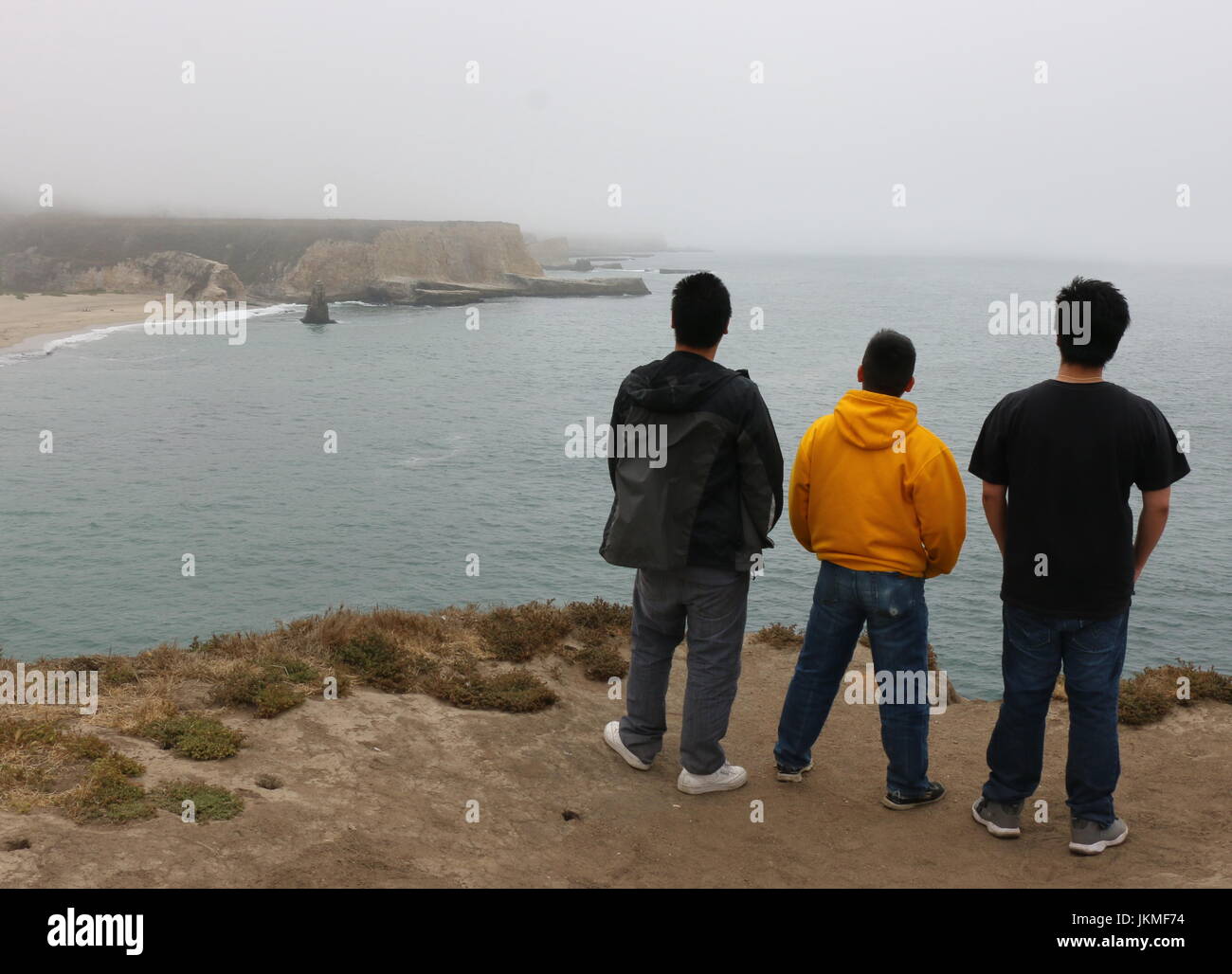 Tre giovani uomini asiatici su una escursione che si affaccia sulla costa della California, Davenport CA. Foto Stock