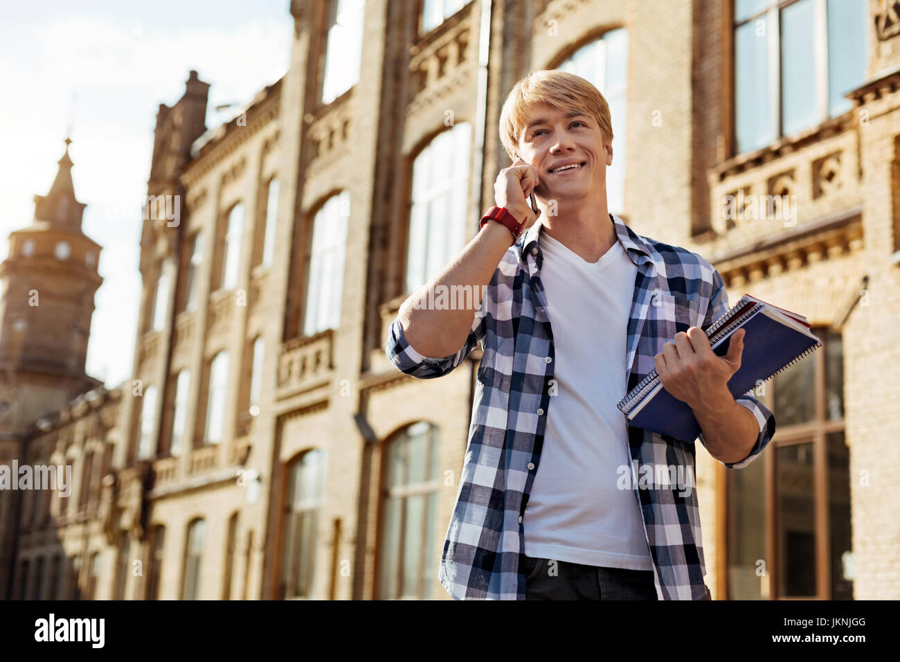 Attraente ragazzo positivo parlare al telefono Foto Stock