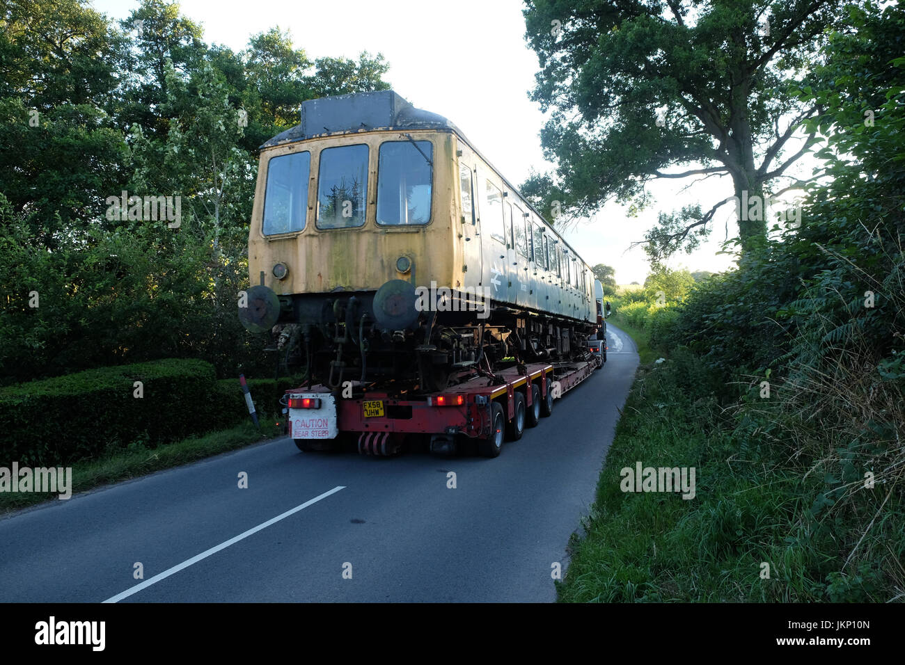 Titley, Herefordshire, Regno Unito - Lunedì 24 Luglio 2017 - Vasta gamma di carico a 8pm - un vecchio treno diesel che viene spostato da uno specialista del veicolo di trasporto con trazione posteriore lungo la stretta B4355 vicino a Kington in rural Herefordshire in rotta verso una nuova casa nel Gloucestershire. Credito: Steven Maggio/Alamy Live News Foto Stock