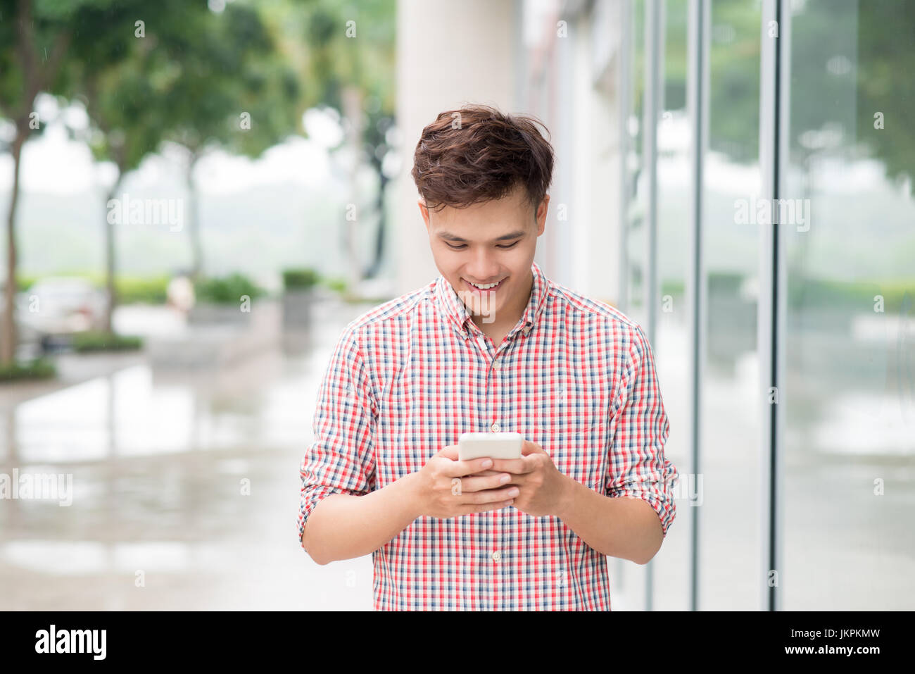 Asian giovane uomo utilizzando smart phone per esterno Foto Stock