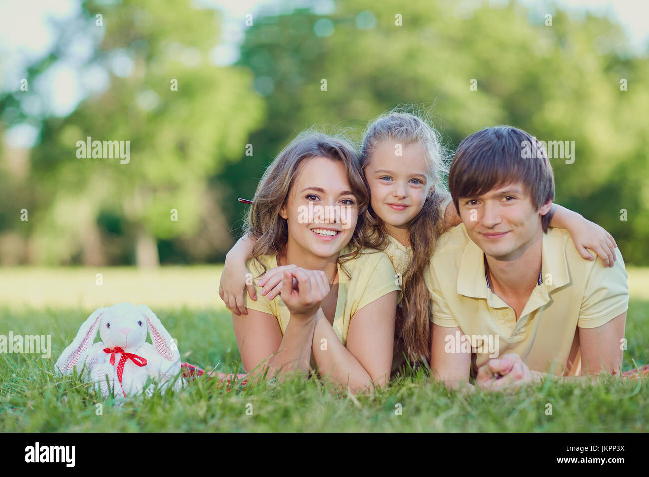 La famiglia felice giacente su erba nel parco Foto Stock