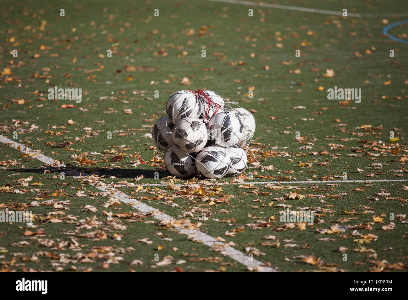 Palloni da calcio in pezza in mezzo caduto foglie secche sul campo da gioco Foto Stock