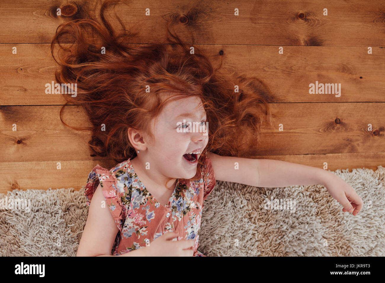 Angolo di alta vista di felice ragazza distesa su un tappeto nel salotto di casa Foto Stock