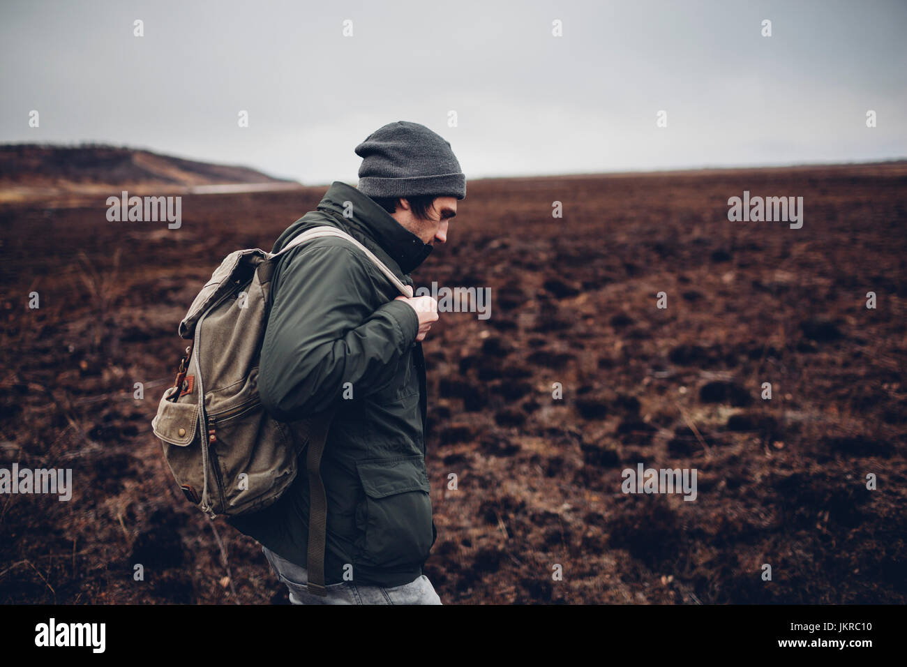 Vista laterale di un escursionista che porta uno zaino mentre camminando sul paesaggio arido, Blagoveschensk, Amur, Russia Foto Stock