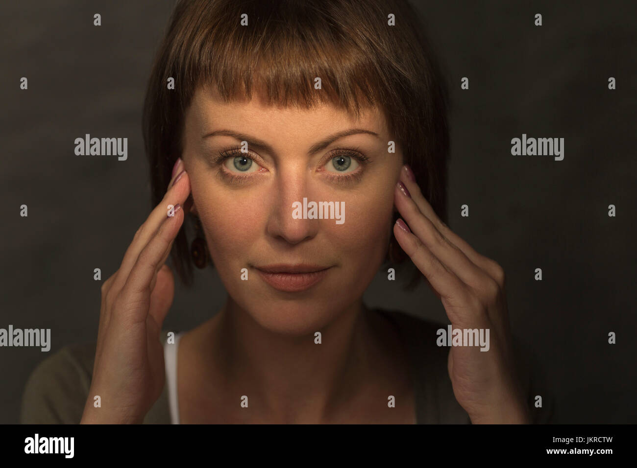 Ritratto di metà donna adulta meditando contro uno sfondo grigio Foto Stock