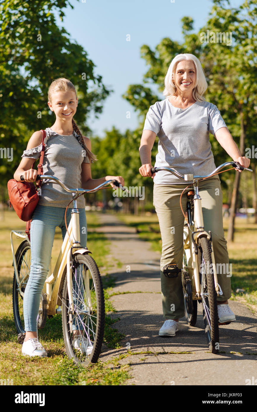 Ragazza positiva e la sua gradnmother equitazione biciclette Foto Stock