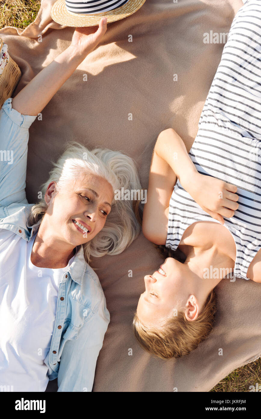 Gioioso donna senior in appoggio su un pic-nic con il suo nipote Foto Stock