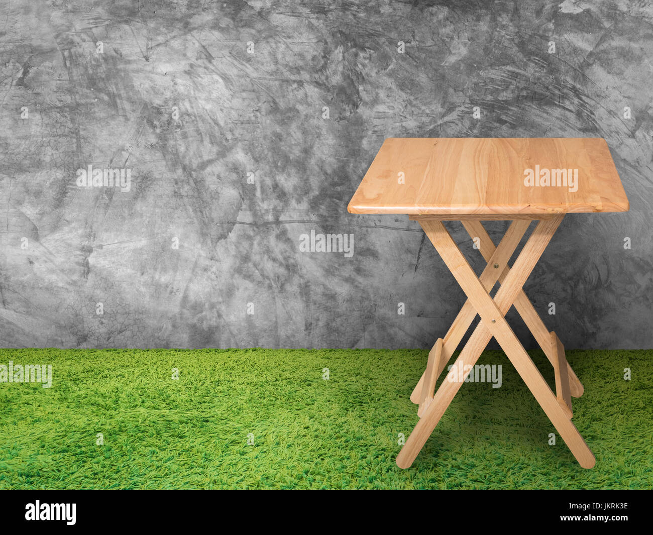 Tavolo in legno con parete in cemento ed erba verde Foto Stock