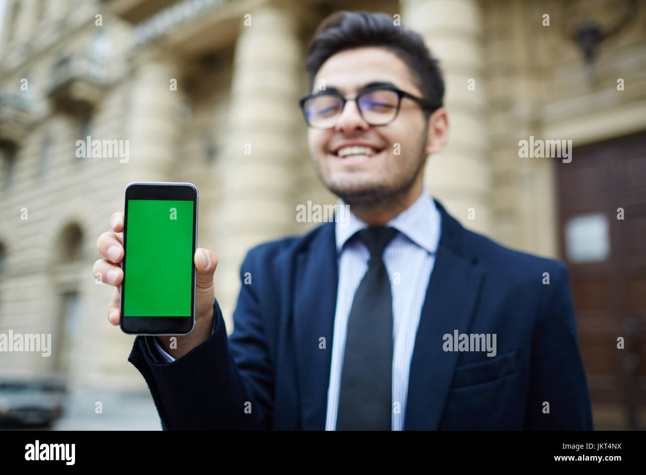 Uomo di successo che mostra un annuncio del programma bonus nel suo smartphone Foto Stock