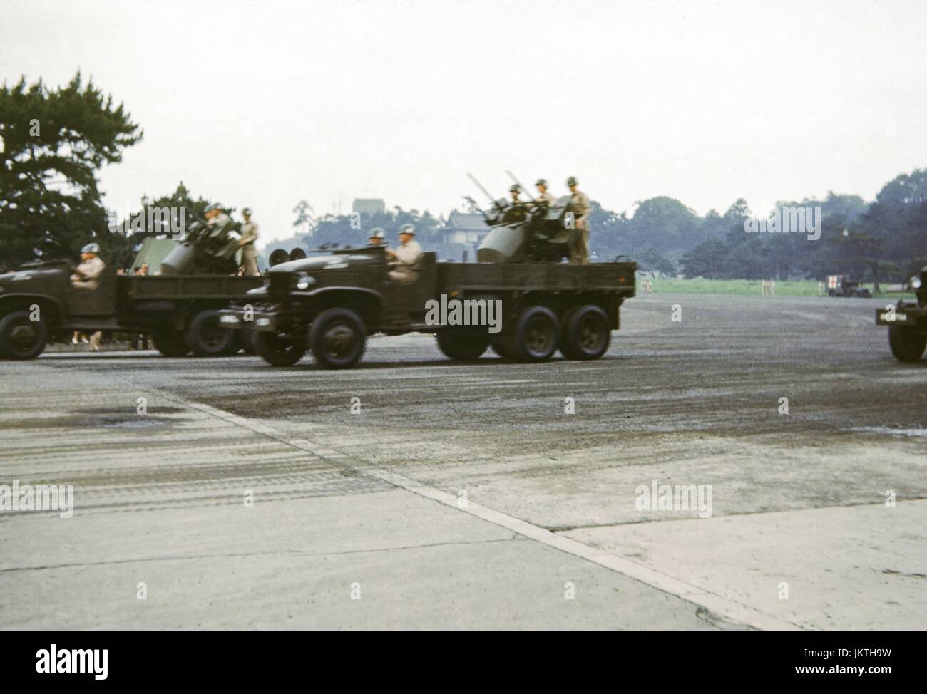 Camion militari con mitraglieri guidare attraverso un campo di aviazione militare in Giappone, 1952. Foto Stock