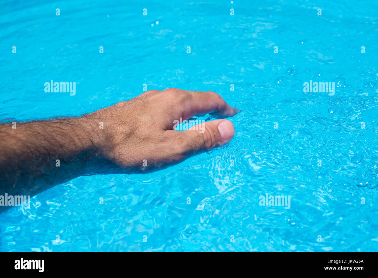 Maschio lato toccando Cancella piscina acqua, attività estiva a bordo piscina Foto Stock