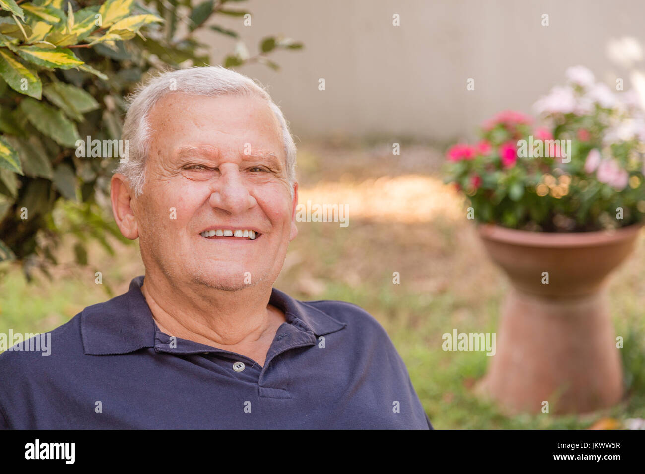 Ritratto di felice uomo vecchio con una pelle morbida nel giardino di casa Foto Stock