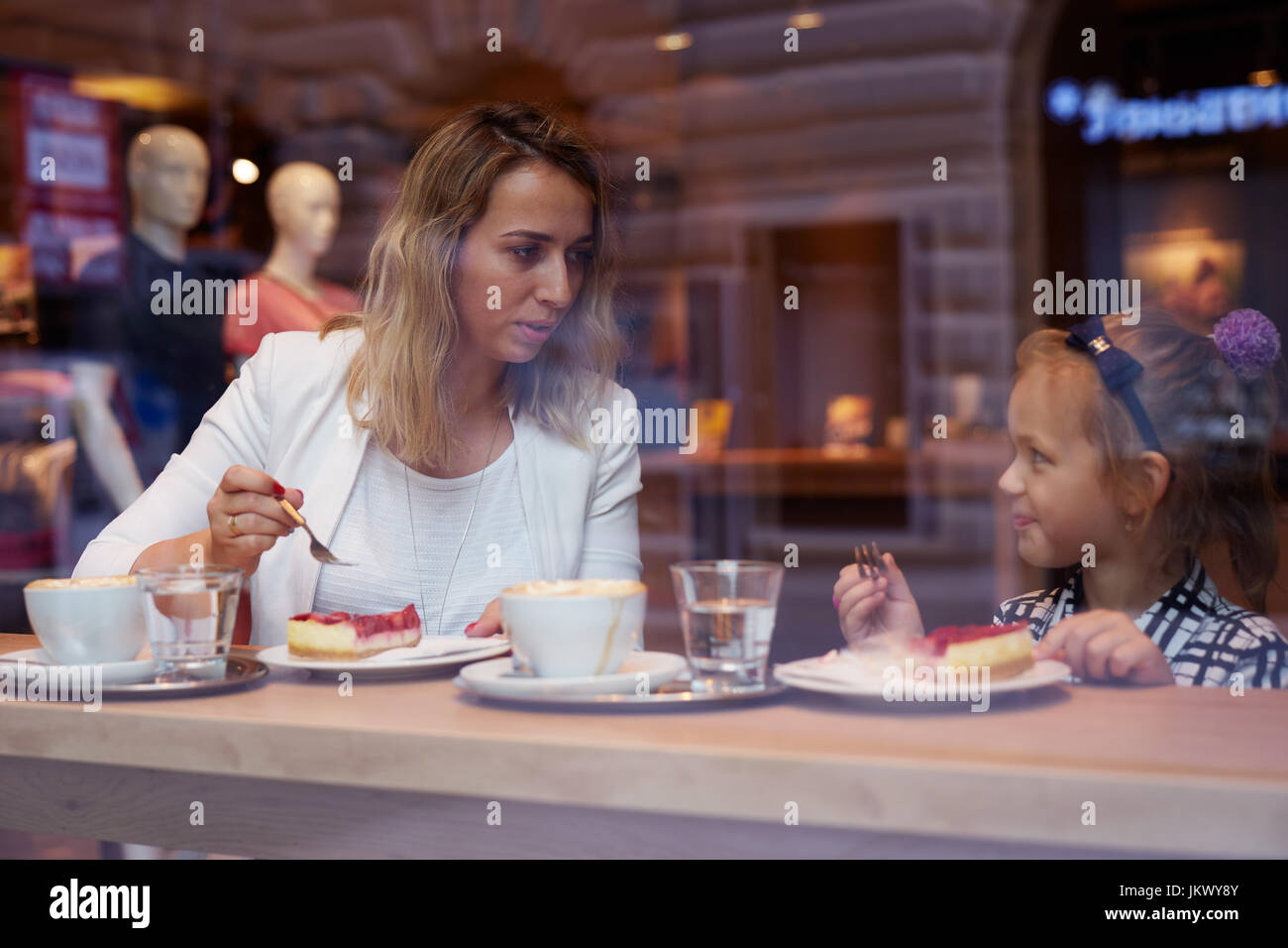 Giovane madre e figlia di trascorrere del tempo in cafe e mangiare la torta Foto Stock