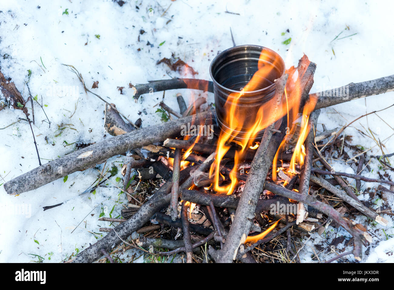 La sopravvivenza in inverno - acqua bollente per il tè su piccoli falò Foto Stock
