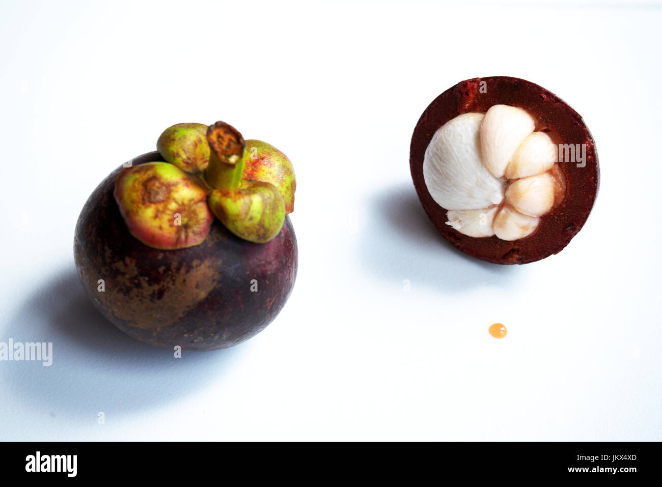 Il mangosteen frutta e una mezza mangosteen frutta con la sua carne bianca esposta preso contro un bianco di sfondo pulito Foto Stock