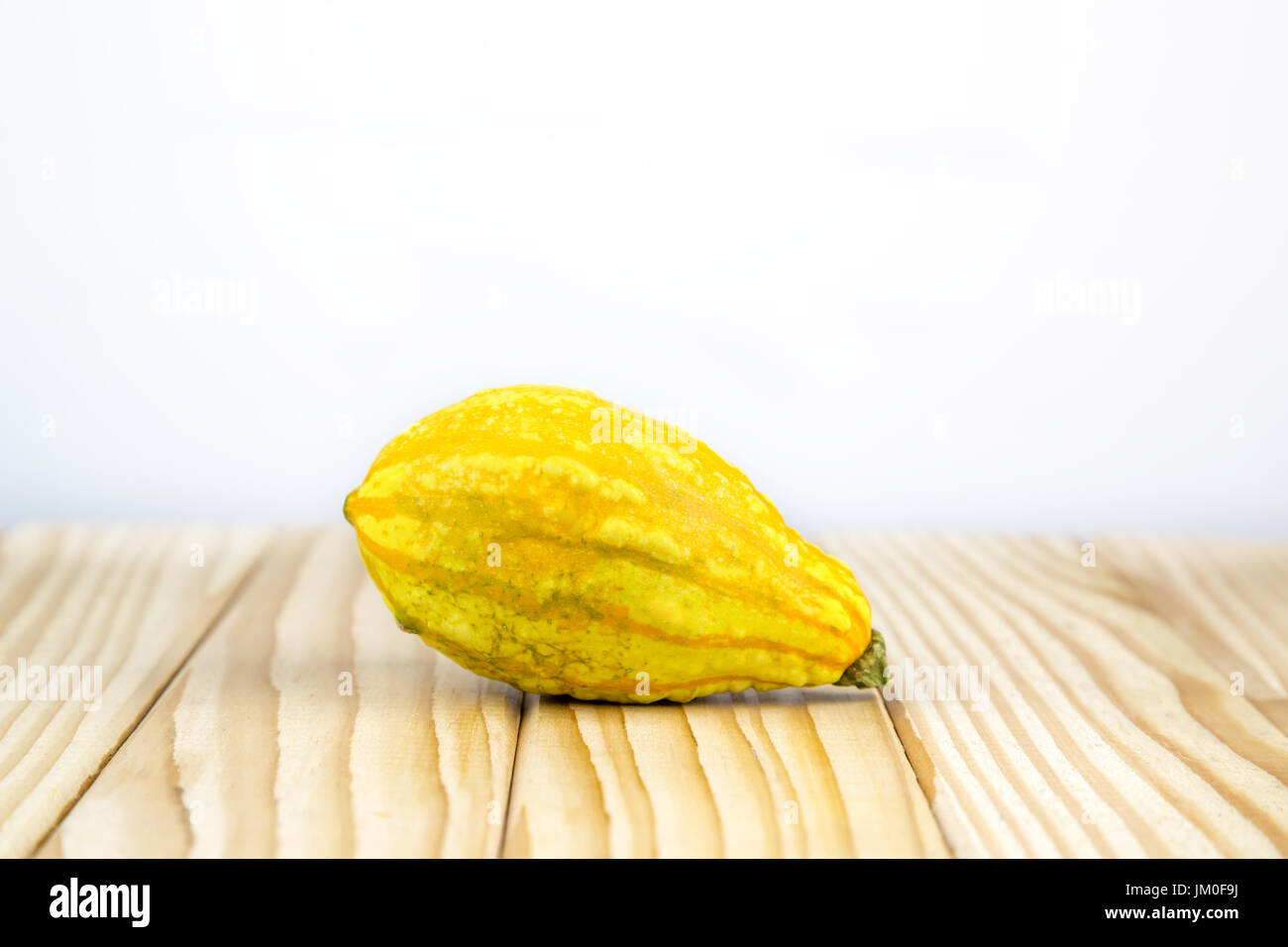 Una zucca decorativa (dolce gnocco) giacente su legno con sfondo per un testo Foto Stock