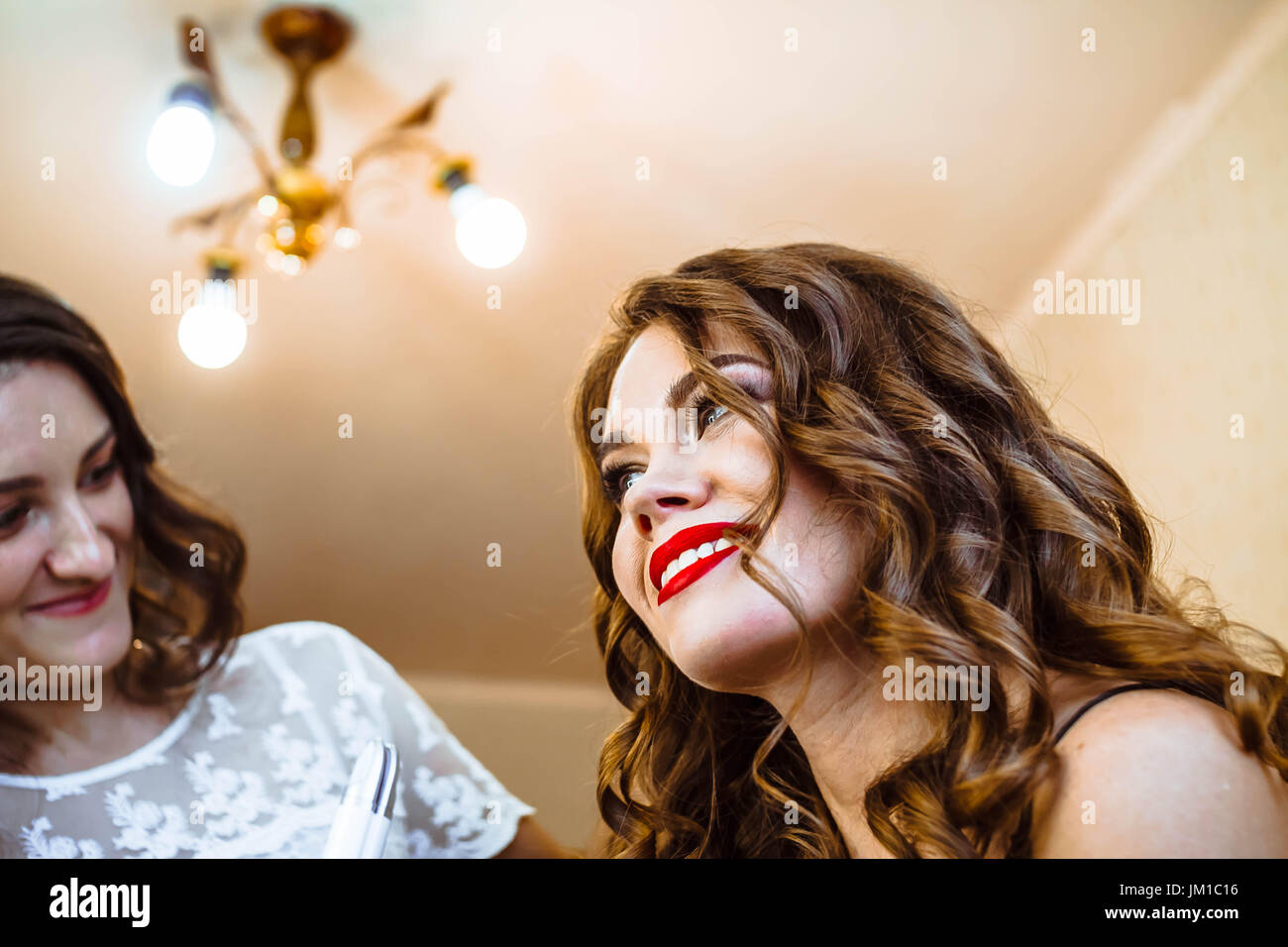 Hair stylist rendendo boccoli di brunette donna. parrucchiere lavora con bella donna capelli nel salone di parrucchiere. Foto Stock