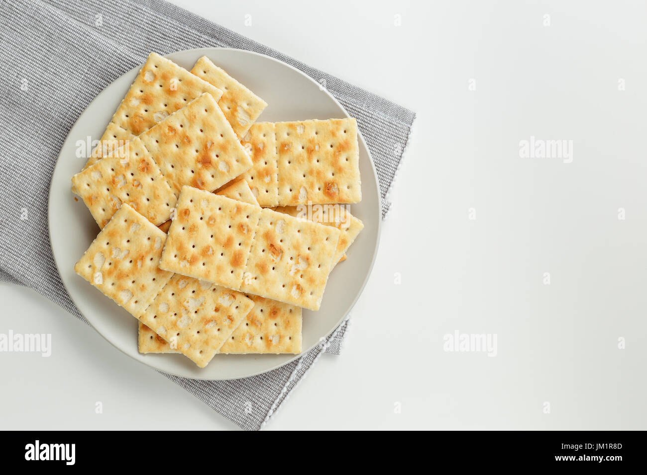 Primo piano di una piastra di uno snack. Pila di cracker sulla piastra di colore grigio e grigio igienico su sfondo bianco Foto Stock