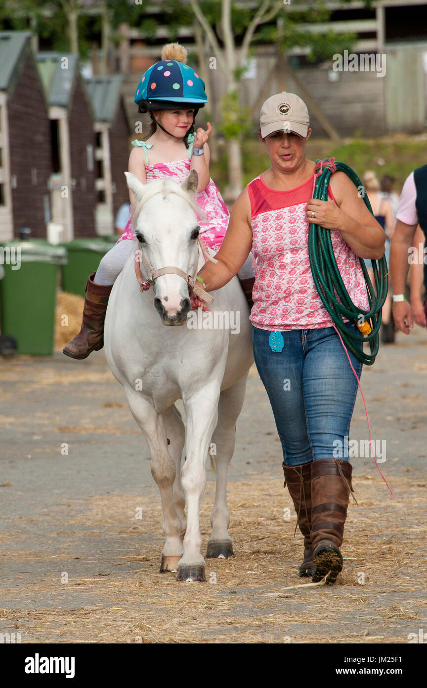 Llanelwedd, Powys, Regno Unito. Xxv Luglio, 2017. Cinque anni di grazia Davies da Abergavenny, Wales, Regno Unito. cavalca il suo bianco Sezione un pony - Abigail attraverso l'area stabile la sera del secondo giorno del Royal Welsh Show. Il Royal Welsh Agricultural Show è salutato come il più grande e più prestigioso evento del suo genere in Europa. In eccesso di 200.000 visitatori sono attesi questa settimana nel corso di questi quattro giorni di periodo di mostra. Il primo film era a Aberystwyth in 1904 ed ha attirato 442 voci di bestiame. Credito: Graham M. Lawrence/Alamy Live News Foto Stock