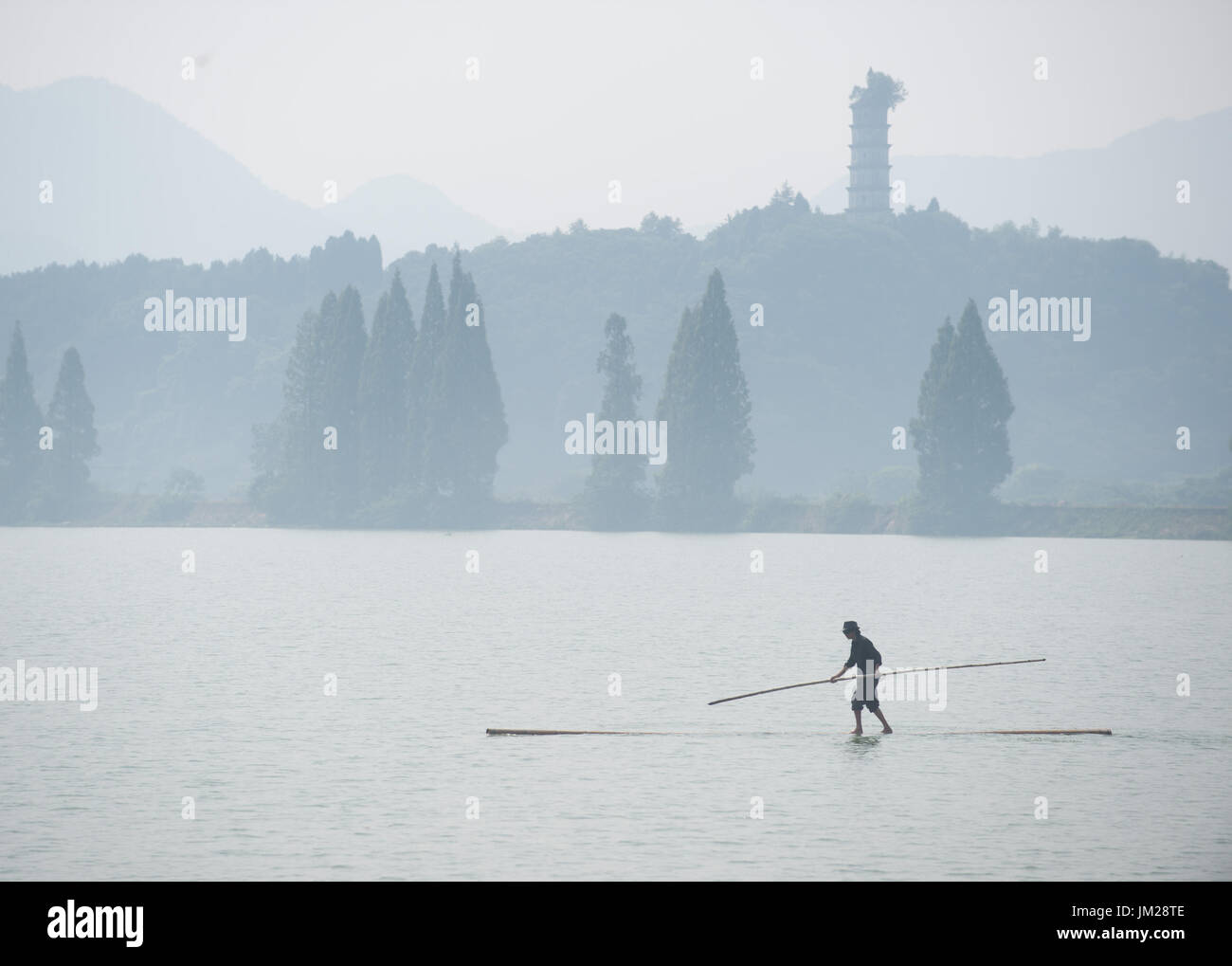 Jiande cinese della provincia dello Zhejiang. 26 Luglio, 2017. Fang Shuyun, 52, nativo di Hangzhou, attraversa Xin"di un fiume con due poli di bambù in città Meicheng, Jiande, Hangzhou, est della Cina di Provincia dello Zhejiang, 26 luglio 2017. Fang ha imparato il trucco dal compagno di concittadini quando egli era un capretto e perfezionato la specialità negli anni. Ora egli diventa il solo che può eseguire il trucco in città. Credito: Weng Xinyang/Xinhua/Alamy Live News Foto Stock