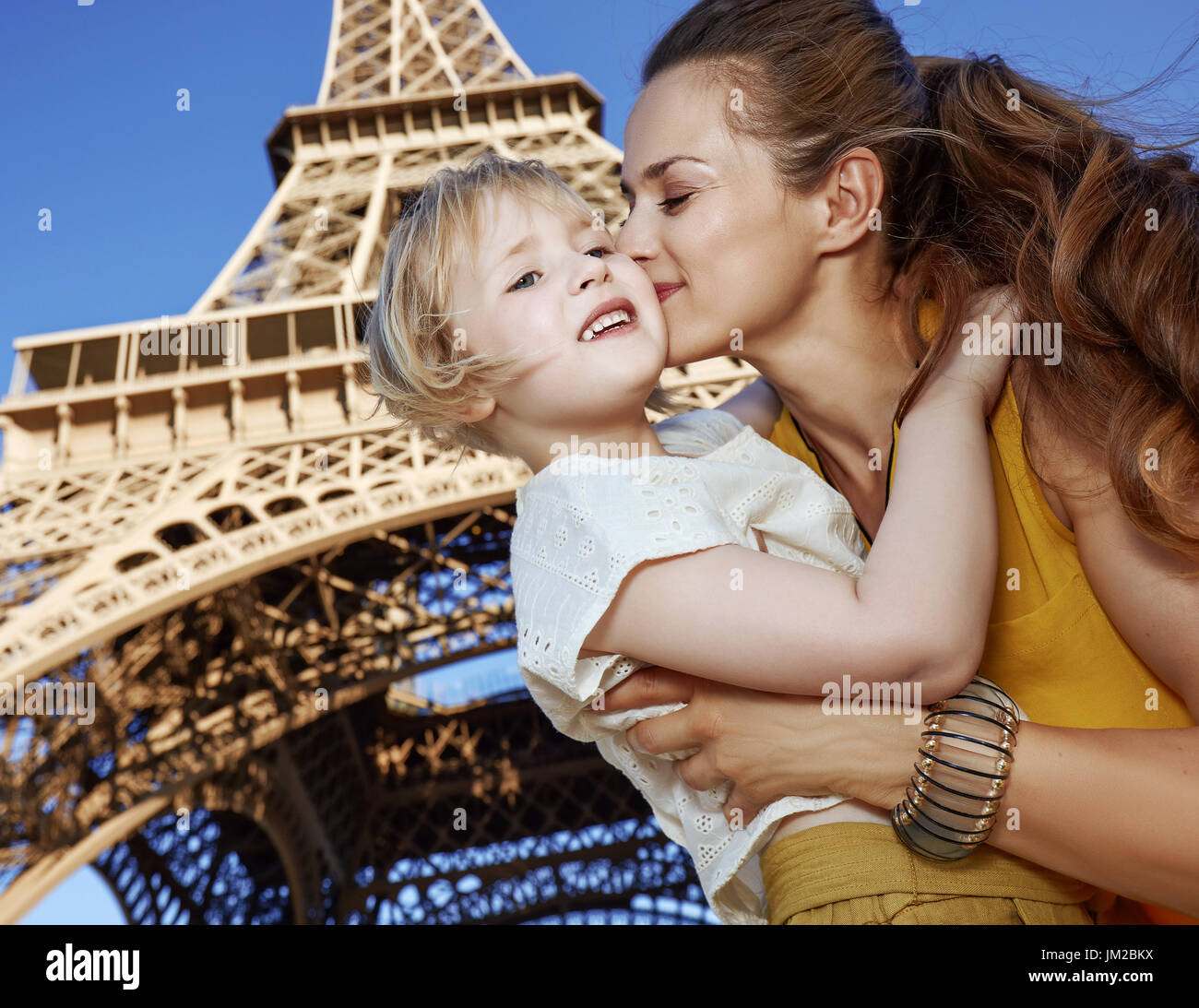 Turistica, senza dubbio, ma ancora in modo divertente. felice la madre e il bambino turisti kissing contro la Torre Eiffel a Parigi, Francia Foto Stock