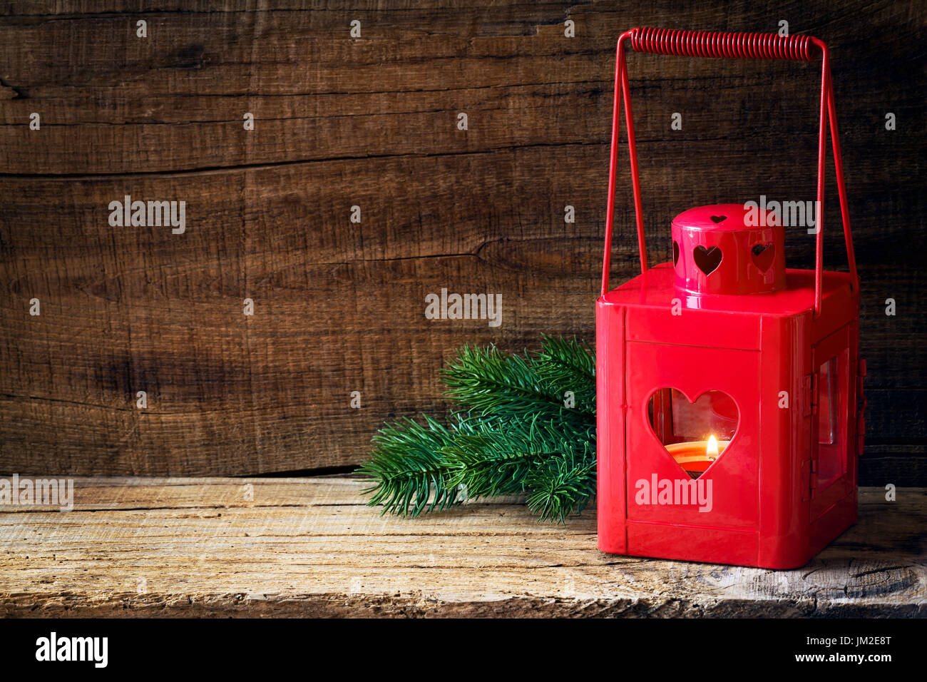 Rosso lanterna di Natale con una candela accesa e rami di abete su scuri in legno rustico sfondo. Con abbondanza di spazio di copia per il testo Foto Stock