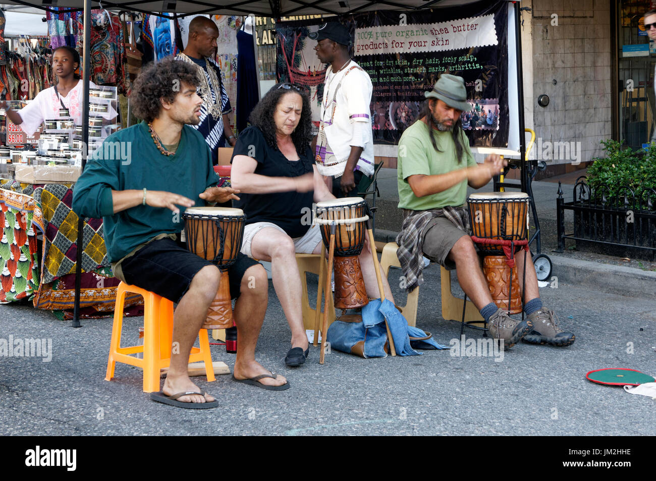 Persone che giocano a West African djembe o jembe calice tamburi sulle unità commerciali, Vancouver, British Columbia, Canada Foto Stock