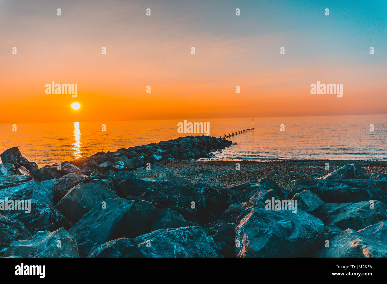 Tramonto nel Galles occidentale sul mare. Preso da Aberaeron. golden sun riflette il mare come si imposta dietro alle rocce e Pier. Foto Stock