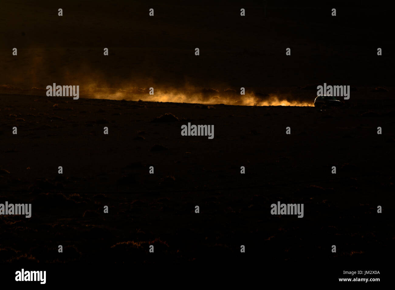 Auto e illuminata di polvere lungo la via del deserto come sole affonda Tindaya Fuerteventura Isole Canarie Foto Stock