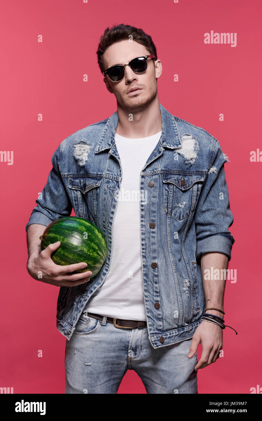 Ritratto di giovane bello uomo informale holding cocomero, attraente giovane uomo Foto Stock