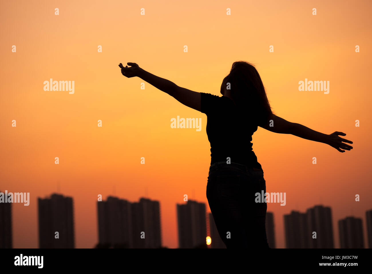 Silhouette di donna di successo in alto le mani con il tramonto sullo sfondo del cielo Foto Stock