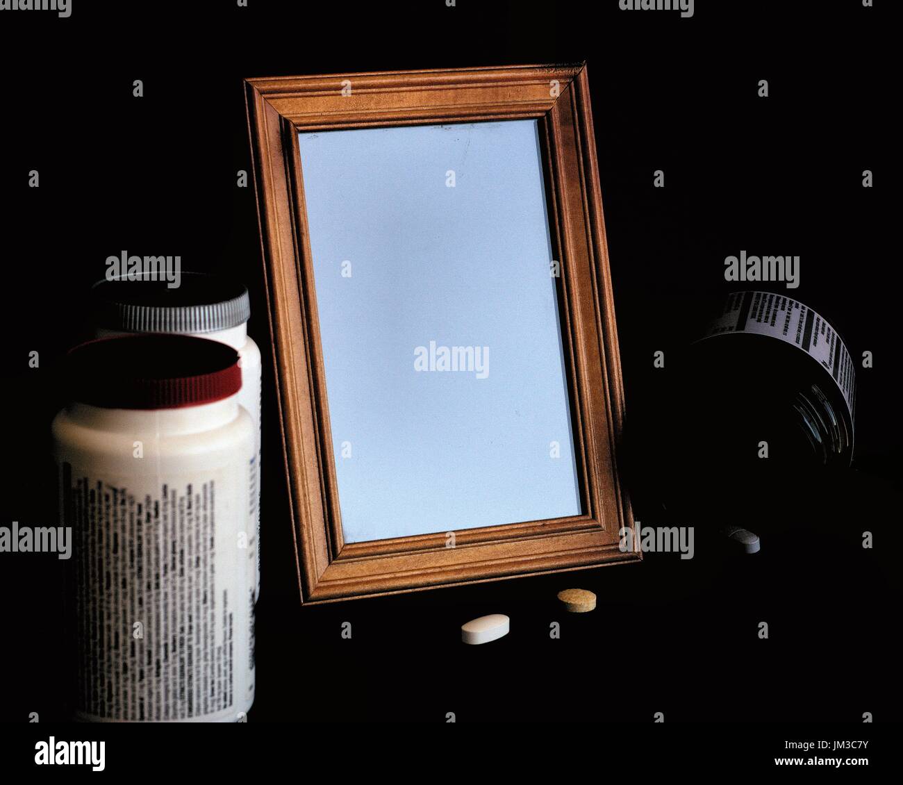 Un buio, inquietanti, morboso immagine di una immagine vuota telaio o cornice fotografica con le pillole di farmaco e medicina bottiglie Foto Stock