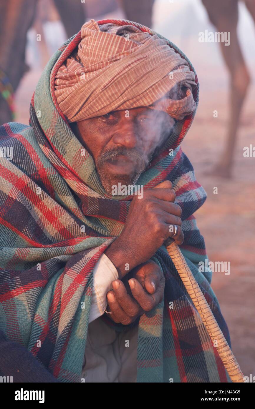Uomo di fumare un narghilè condotto nelle prime ore del mattino presso il Nagaur annuale Fiera del Bestiame nel Rajasthan, India. Foto Stock