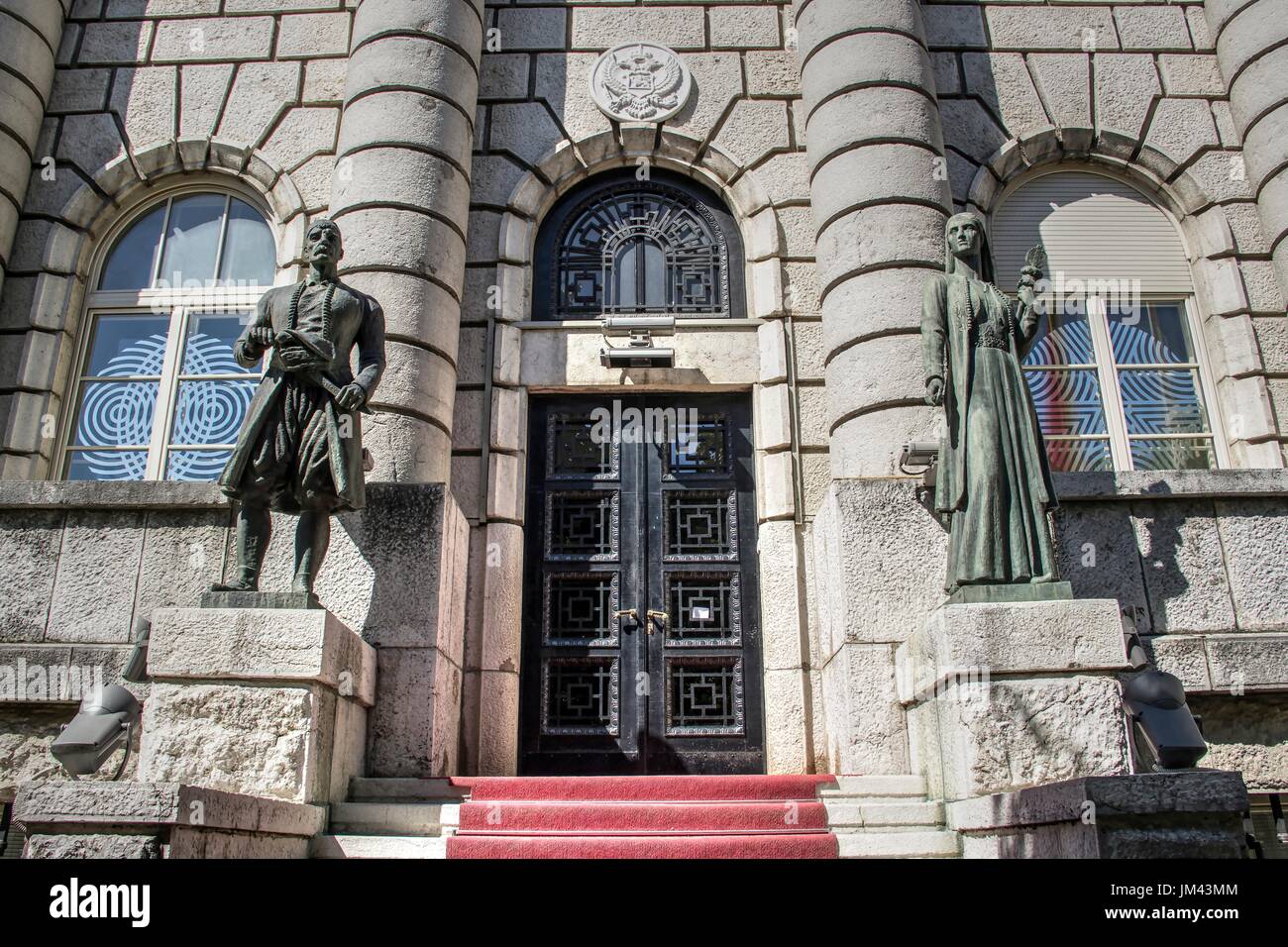 Cetinje, Montenegro - sculture in bronzo di una donna e di un uomo in abiti tradizionali che decorano l'ingresso al Ministero della Cultura Foto Stock