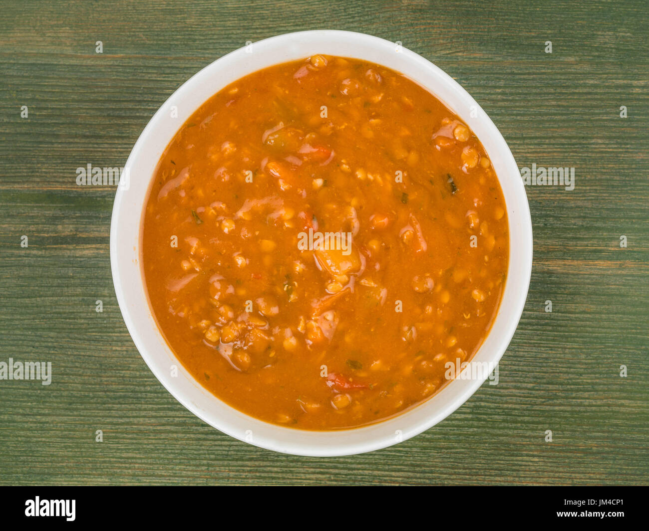 Ciotola di chunky e lenticchie zuppa di bacon contro un verde sullo sfondo di legno Foto Stock