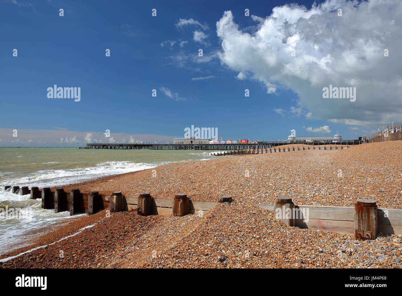 La pittoresca spiaggia di Hastings con il Molo (ricostruita e aperta al pubblico nel 2016) sullo sfondo e un cielo blu con nuvole di Nizza, Hastings, Regno Unito Foto Stock